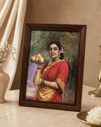 Framed Ravi Varma painting depicting a woman in a red saree holding a fruit platter.