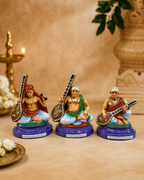 Set of three colorful Sangeetha Mumoorthigal figurines displayed on a table.