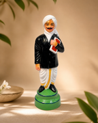 Bharathiyar Standing Figurine, colorful decorative piece, cultural icon, on display surrounded by plants.