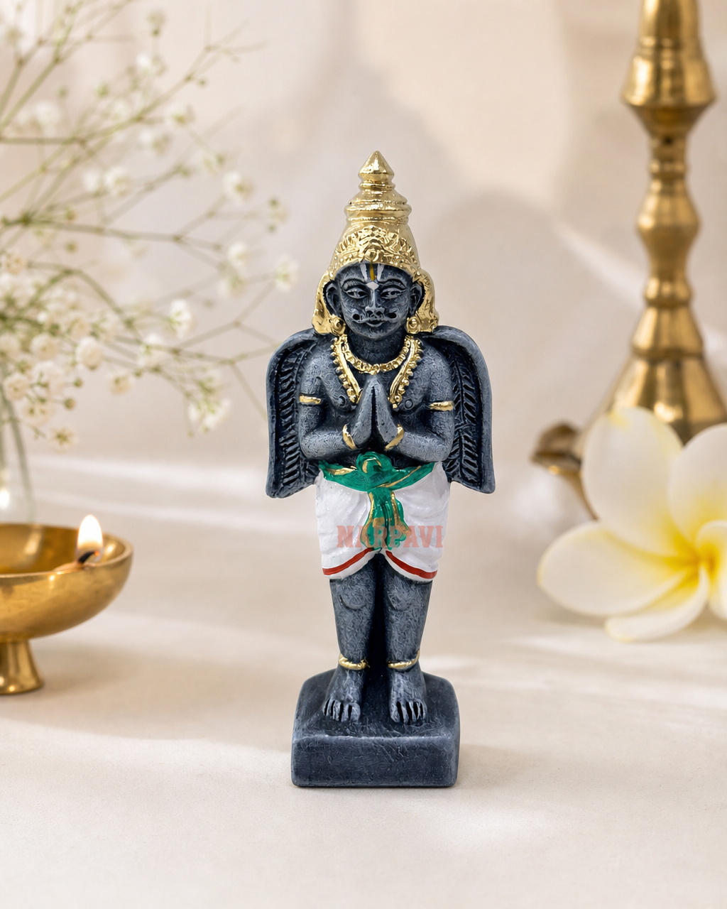 Garudan figurine on a table with floral background and candle