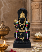 Exquisite black and gold Mariamman small statue with colorful details, incense, and flowers in the background.