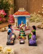 Decorative Saraswati Pooja set with figures and vibrant temple backdrop.