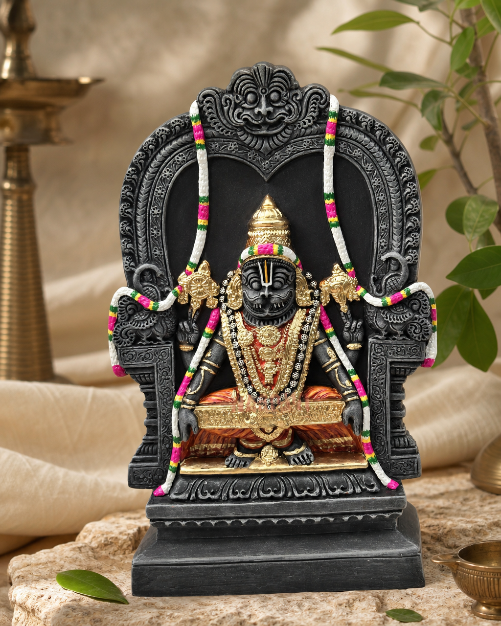 Elegant Yoganarasimha statue with intricate details, adorned with garlands, seated on a decorative throne, surrounded by foliage.