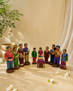 Colorful figurine set depicting a birthday celebration with people in traditional attire surrounding a cake.