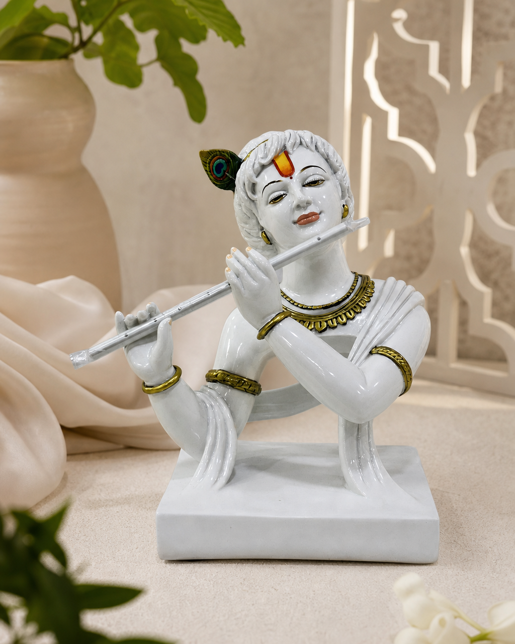 White statue of Krishna playing a flute with ornate jewelry.