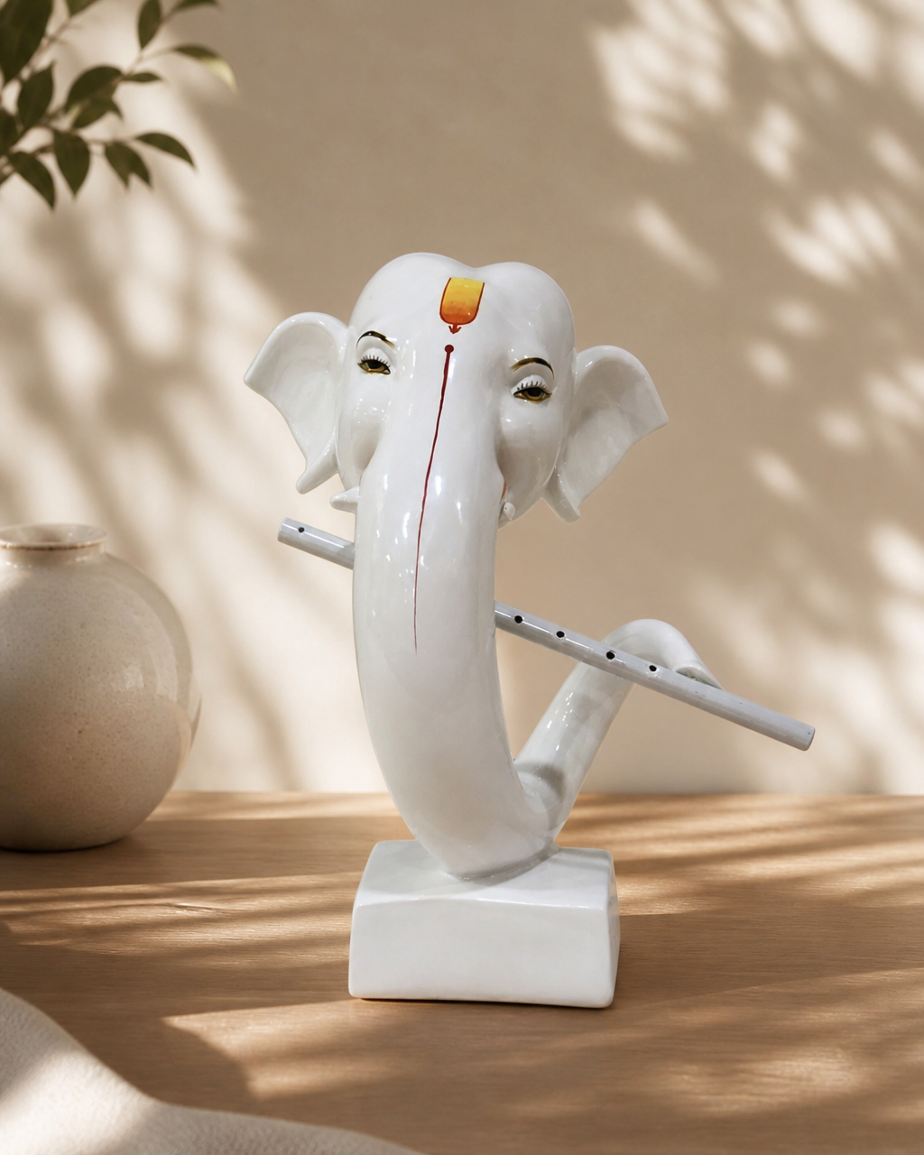Elegant white elephant figurine with a flute on a wooden surface, surrounded by soft shadows and a ceramic vase.