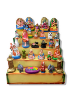 Colorful Miniature Golu Doll Set featuring traditional figures and vibrant designs, arranged on a tiered platform for festive decor.