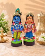 A vibrant Bala Radha Krishna Paper Mache figurine set, showcasing detailed craftsmanship with colorful attire on a decorative background.