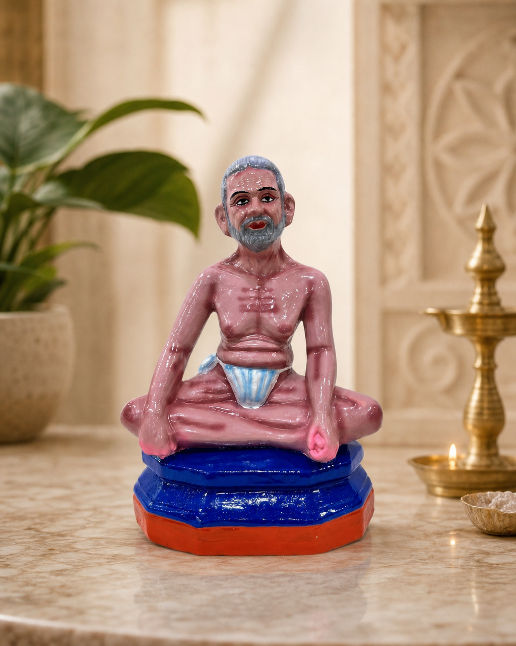 A colorful figurine of Ramana Maharishi seated on a decorative base, ideal for home decor.