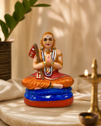 Handcrafted Ramanujar Paper Mache statue with vibrant colors and intricate details, set on a decorative table.