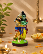 Colorful figurine of Rama and Hanuman embracing, set against a serene background with flowers and a diya.