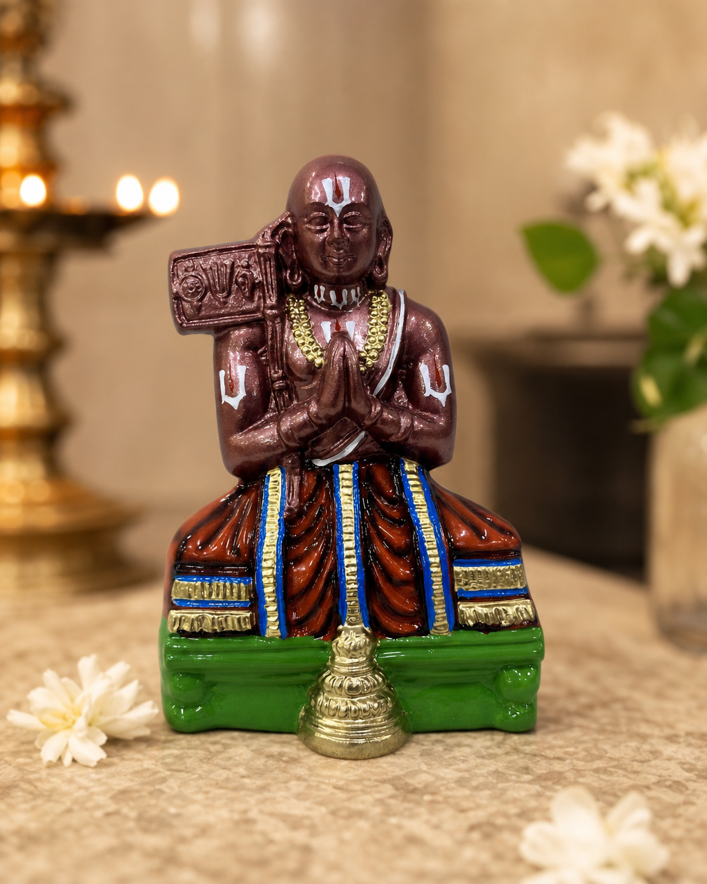 Ramanujar statue with intricate details, adorned in colorful robes, placed on a decorative surface.