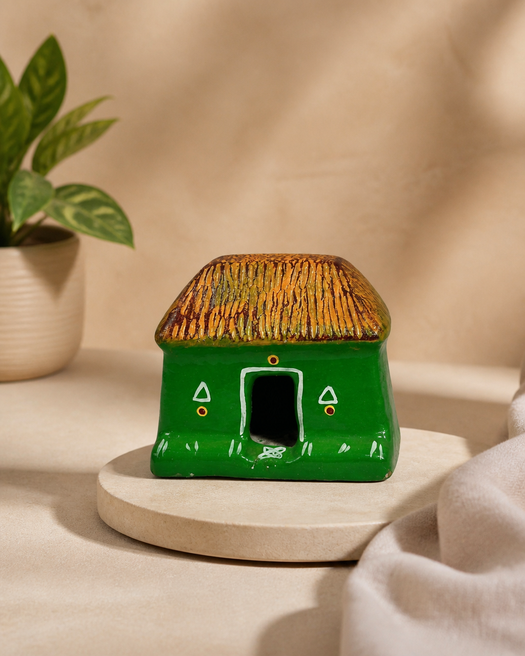 Green and brown clay house figurine with detailed design on a light background