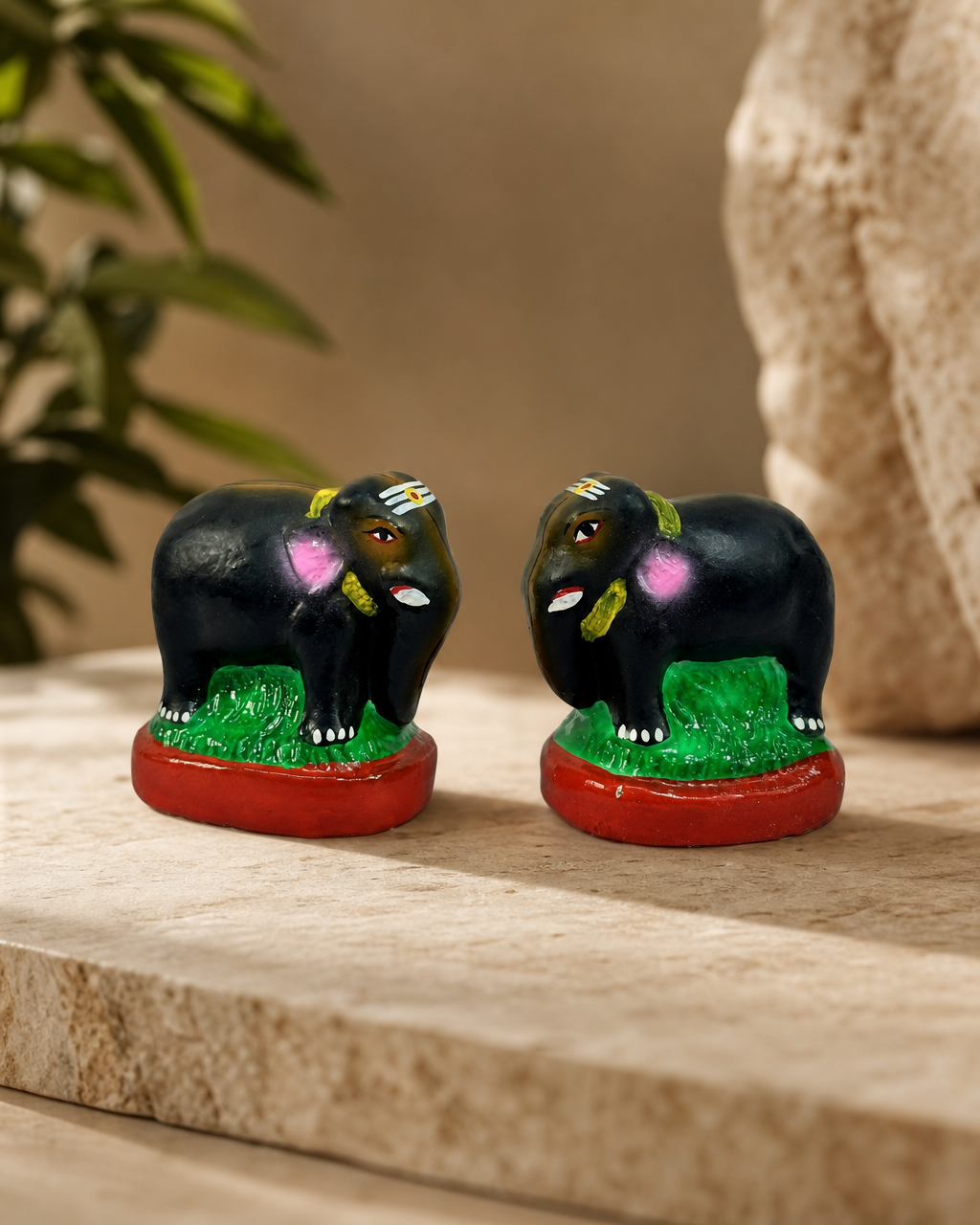 A pair of colorful Jodi Yaanai elephant figurines with intricate details displayed on a stone surface.