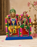 Colorful statue of Meenakshi and Sundareswarar seated together adorned with intricate details.