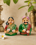Colorful Mysore Raja Rani figurines displayed with decorative backdrop.