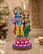 Colorful statue of Nindra Narayanan and Lakshmi with intricate details, placed on a decorative base.