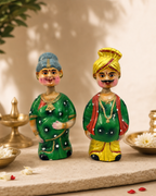 Two colorful Nindra Thaata Paati figurines in traditional attire displayed on a decorative surface.