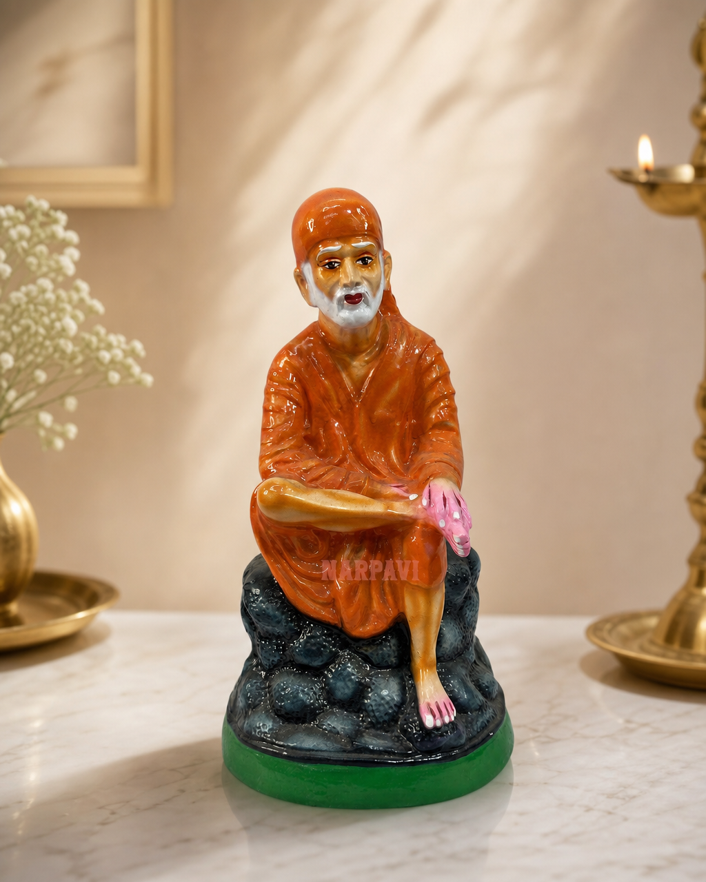 Sai Baba statue in orange attire sitting on a stone-like base, ideal for spiritual decor.