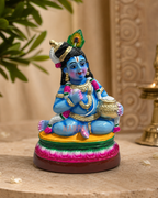 Colorful Urkantha Vennai Kannan figurine displaying intricate details and vibrant colors on a decorative base.