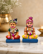 Colorful Hindu wedding couple figurines on a marble surface.