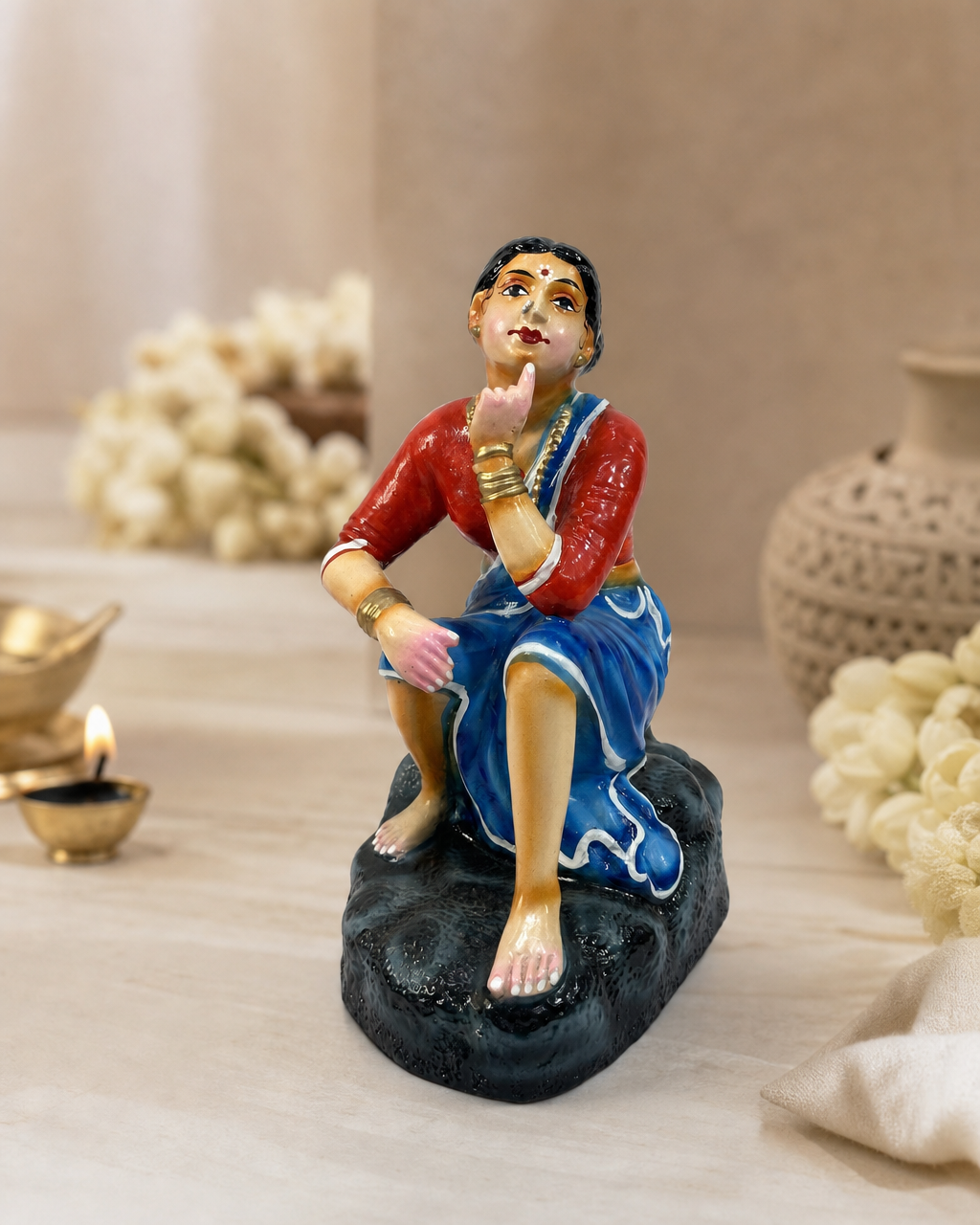 Colorful Utkaarnda statue pen holder in traditional attire, sitting thoughtfully.