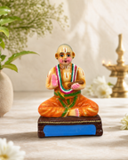 Colorful Vedandha Desikar Figurine with intricate details, placed on a table with flowers and a lamp in the background.