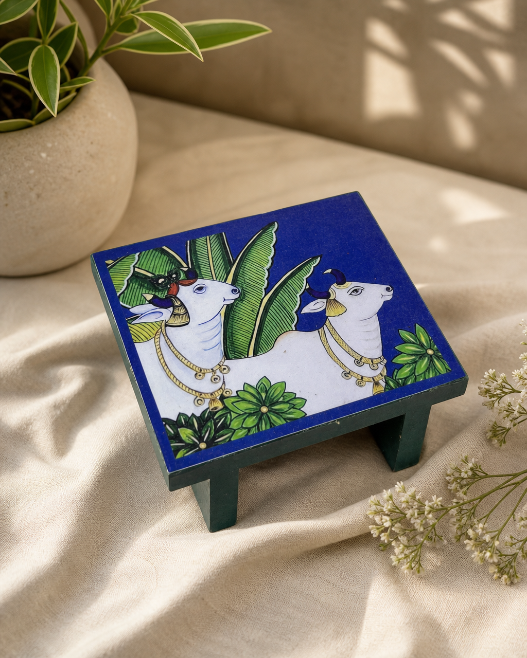 Decorative table with artistic design featuring cows and leaves.
