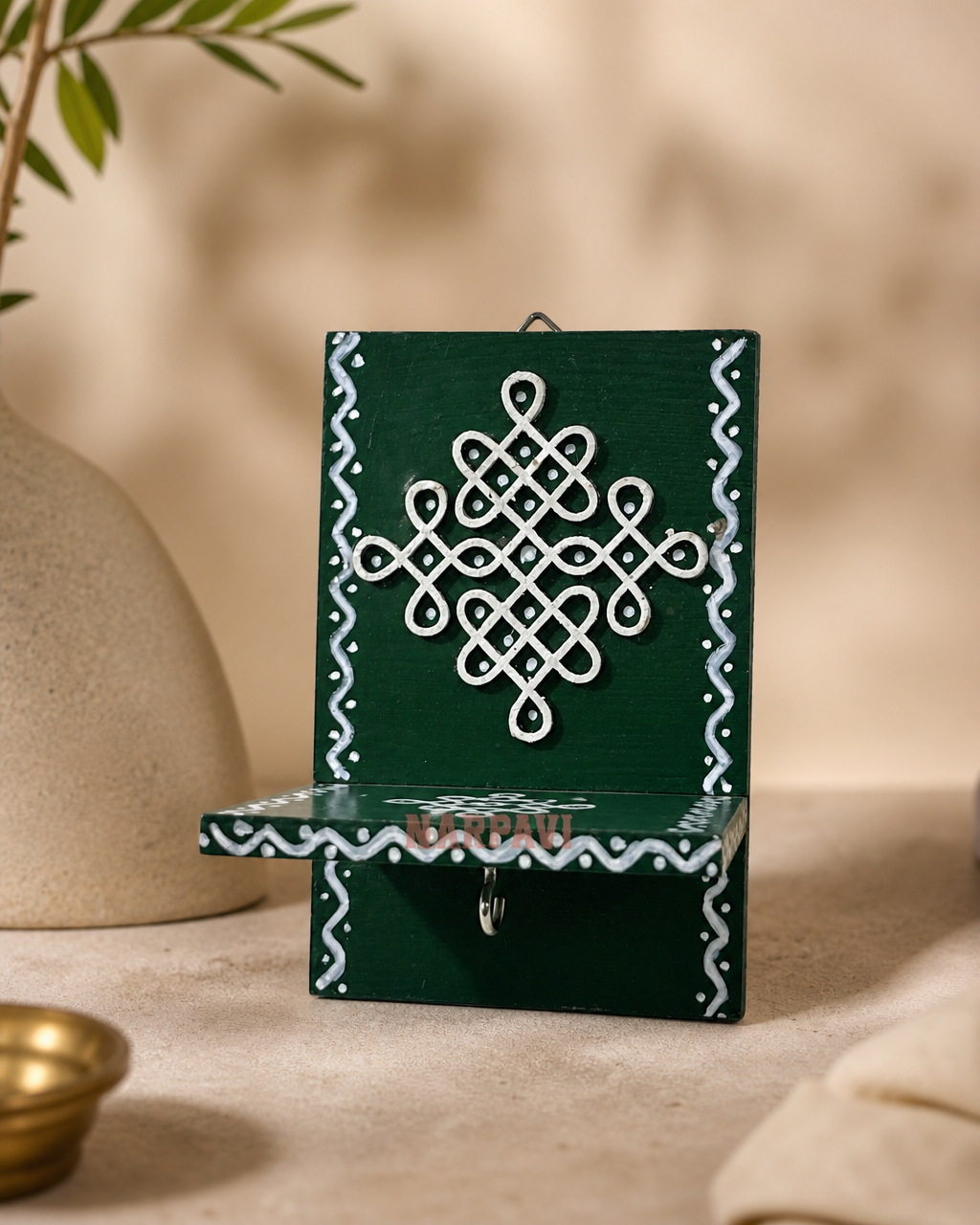 Elegant hanging Kolam art design with intricate patterns on a green background.