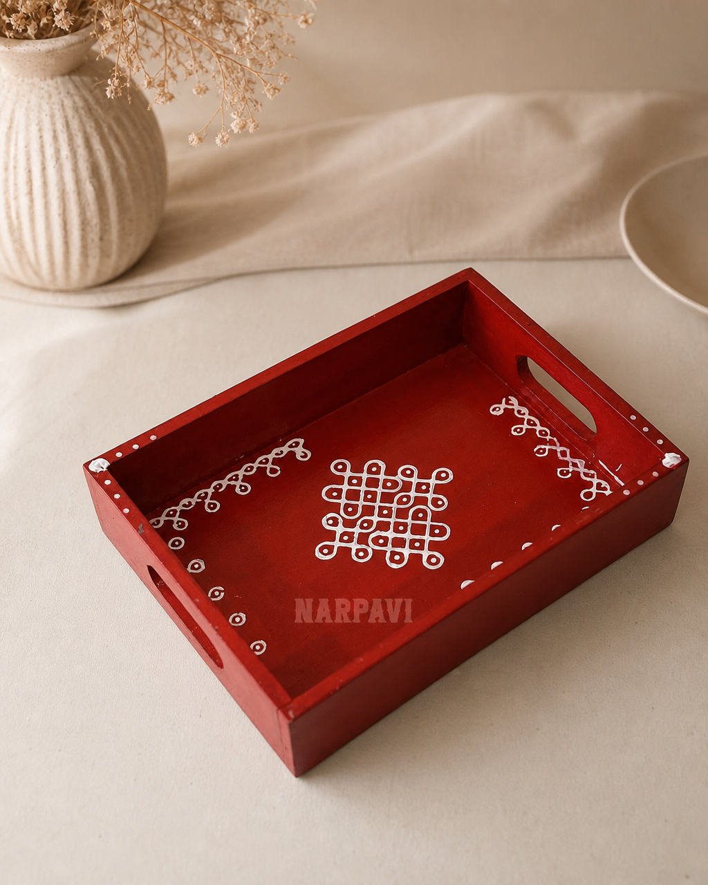 Decorative red tray with handle and white designs on a neutral background